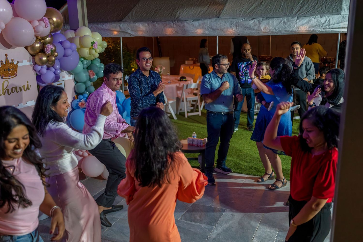 Festive outdoor party scene with colorful balloons and string lights creating a celebratory atmosphere.