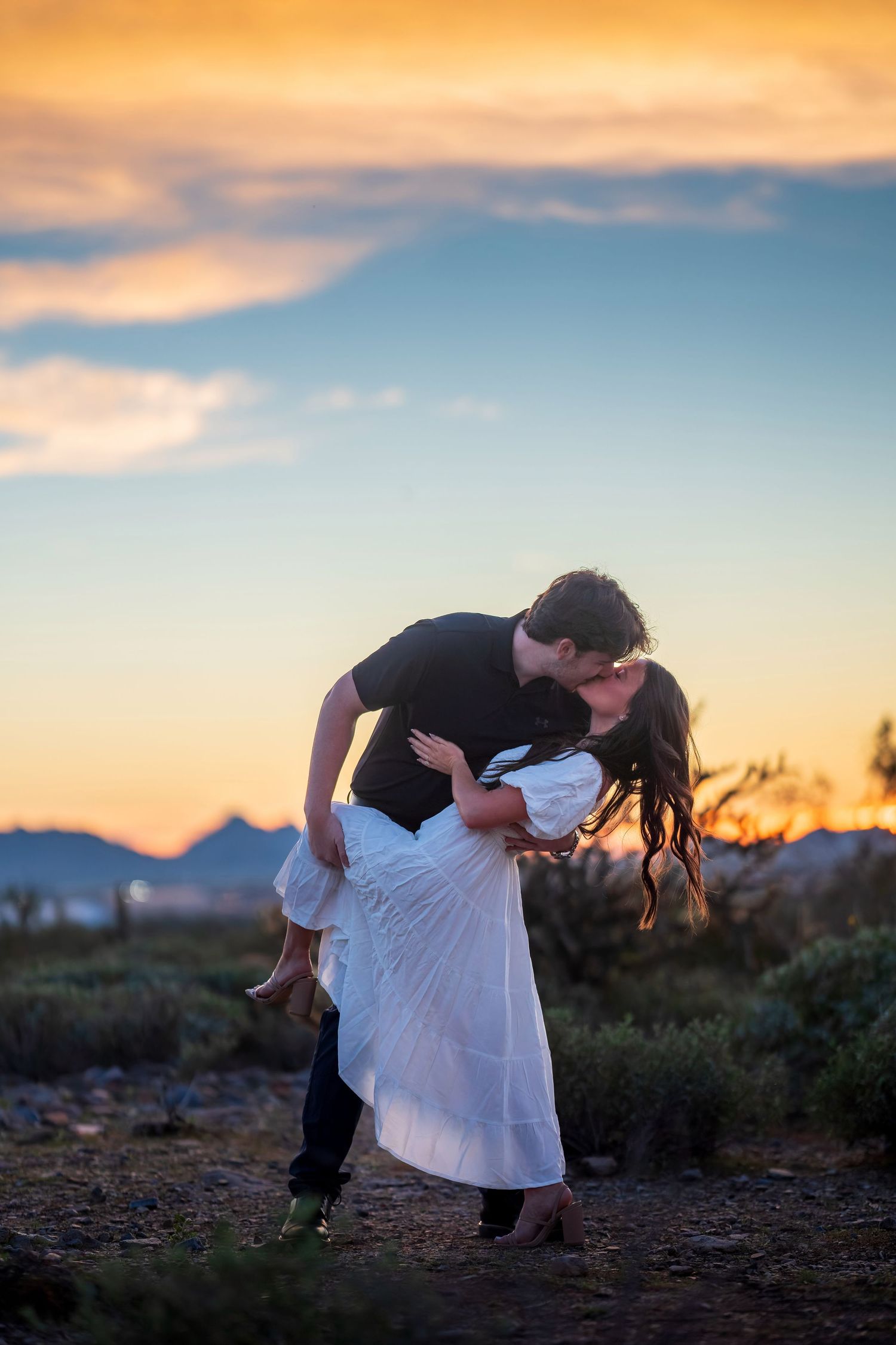 A romantic dip pose captured during golden hour in a desert landscape.