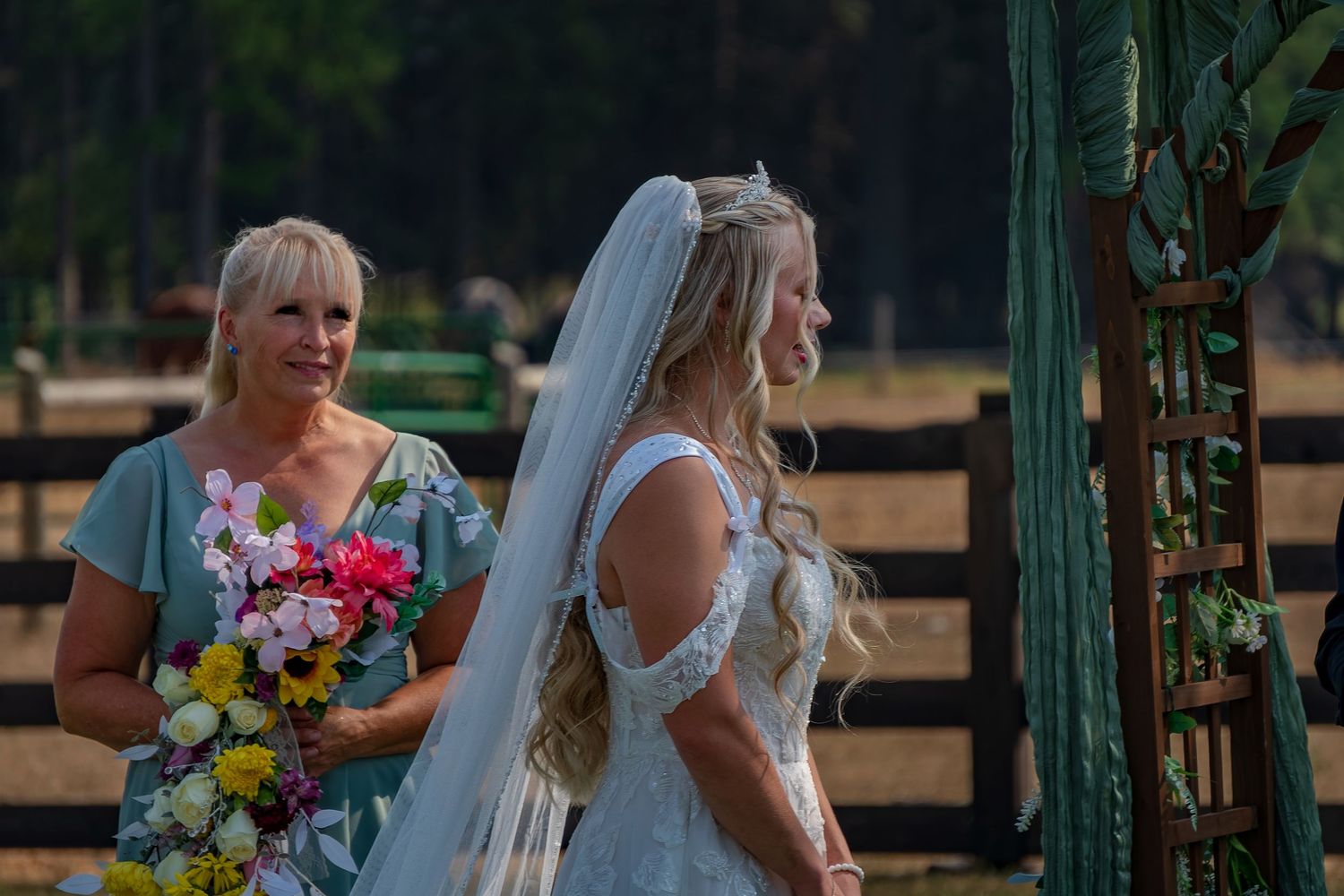 Colorful wedding bouquets pop against the green mountain landscape during an outdoor ceremony.