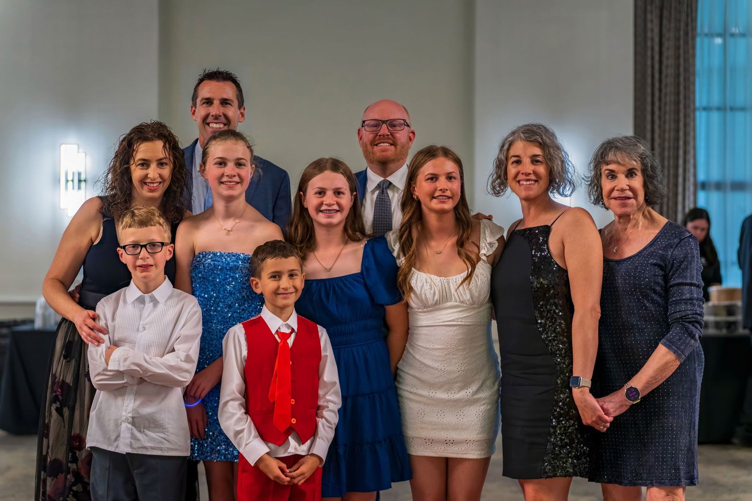 Large family group poses together smiling at a formal event in an elegant venue.