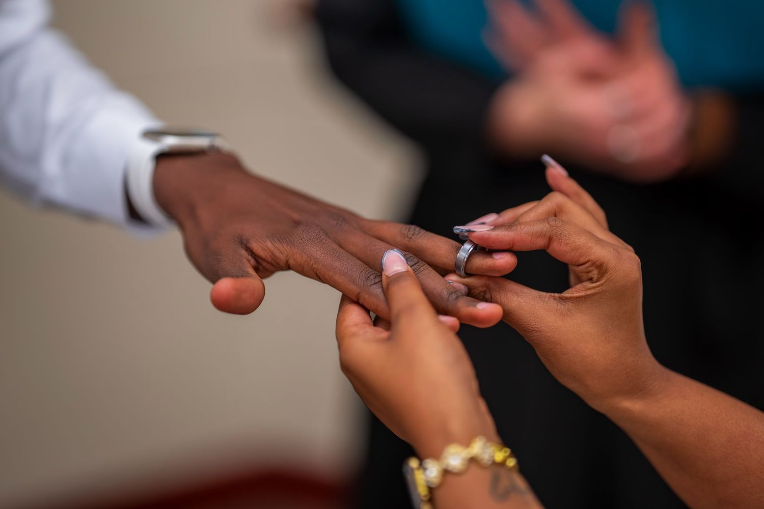 A man sliding a diamond engagement ring onto a woman's finger during a proposal ceremony.