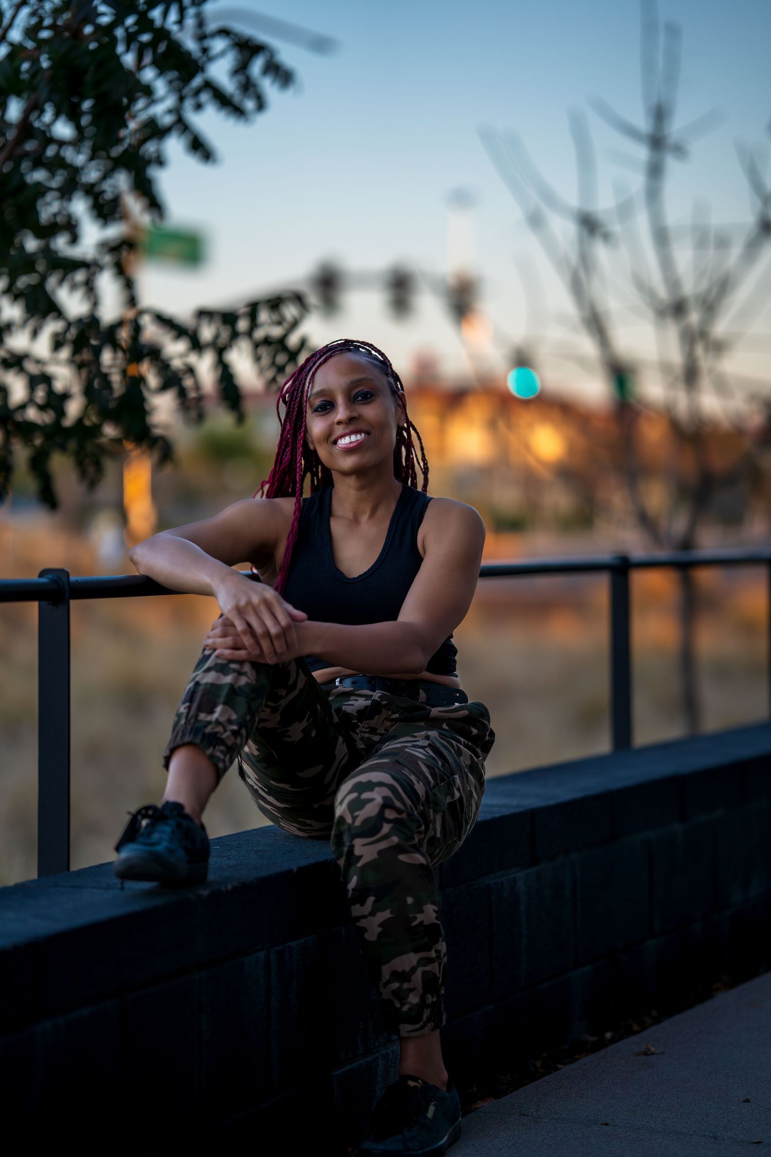 Urban lifestyle portrait with camouflage pants against sunset cityscape.