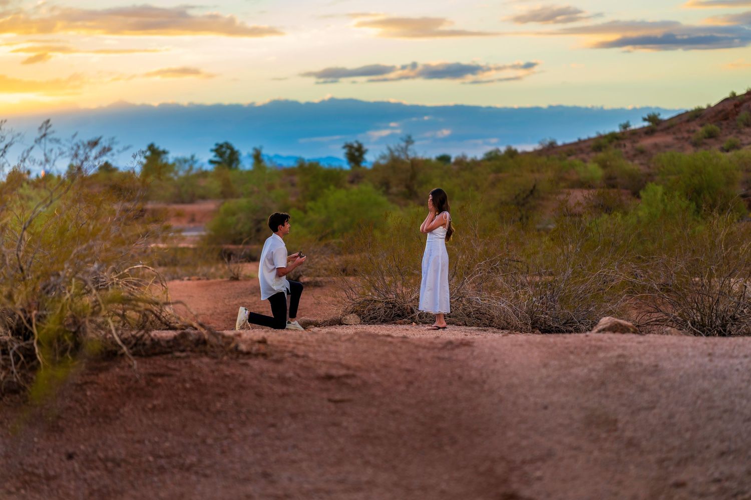 A romantic moment captured in the Arizona desert with dramatic sunset skies.