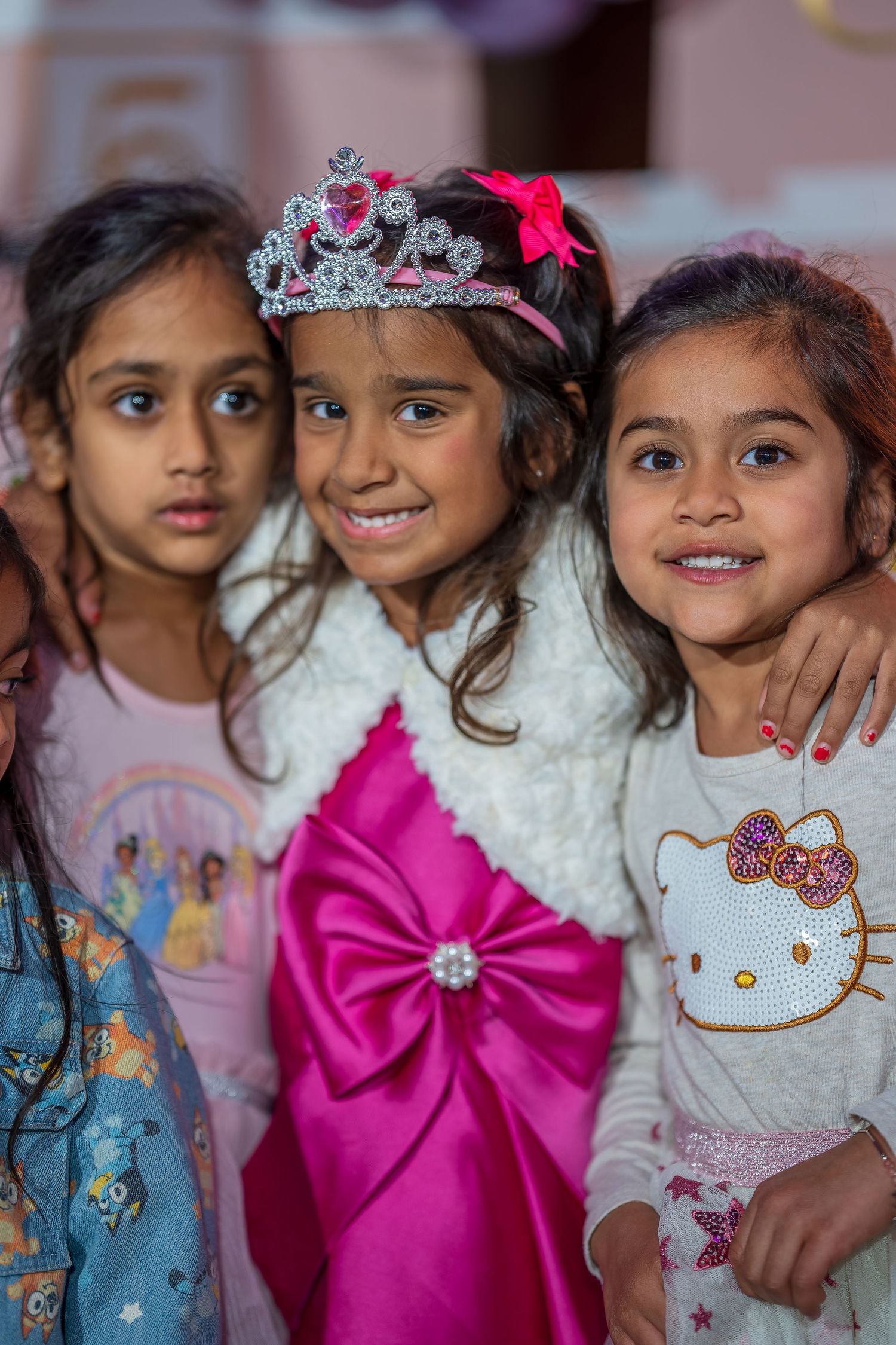 Children wearing party outfits and tiaras gather together for a group photo at a celebration.