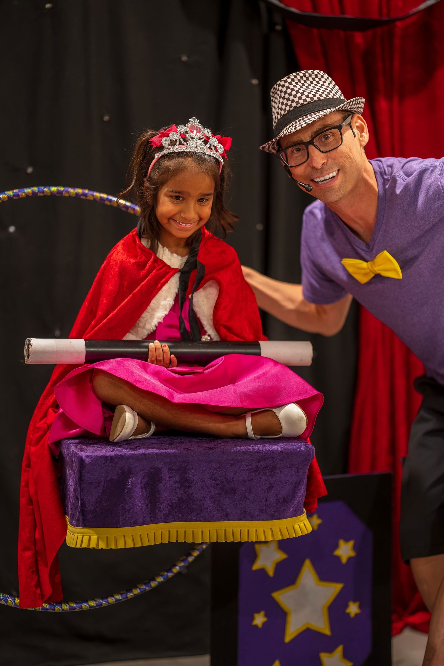 Interactive magic show scene with performers and a decorated purple prop table.