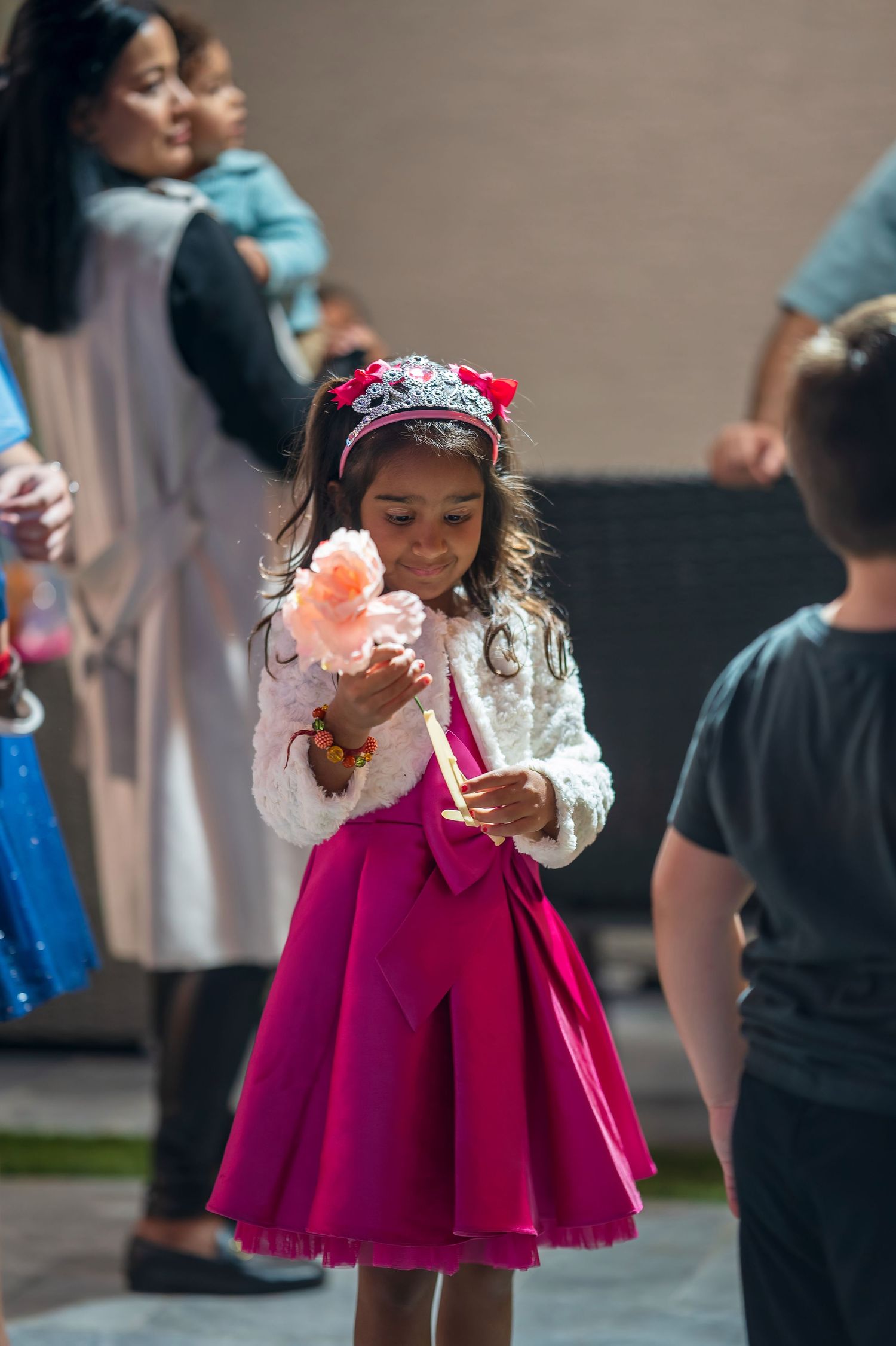 A young dancer in a magenta dress and white top performs at an indoor event.