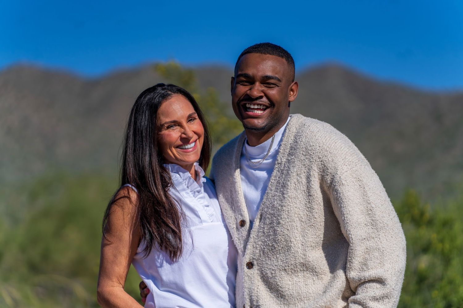 Couple laughing together in front of scenic desert mountain landscape.