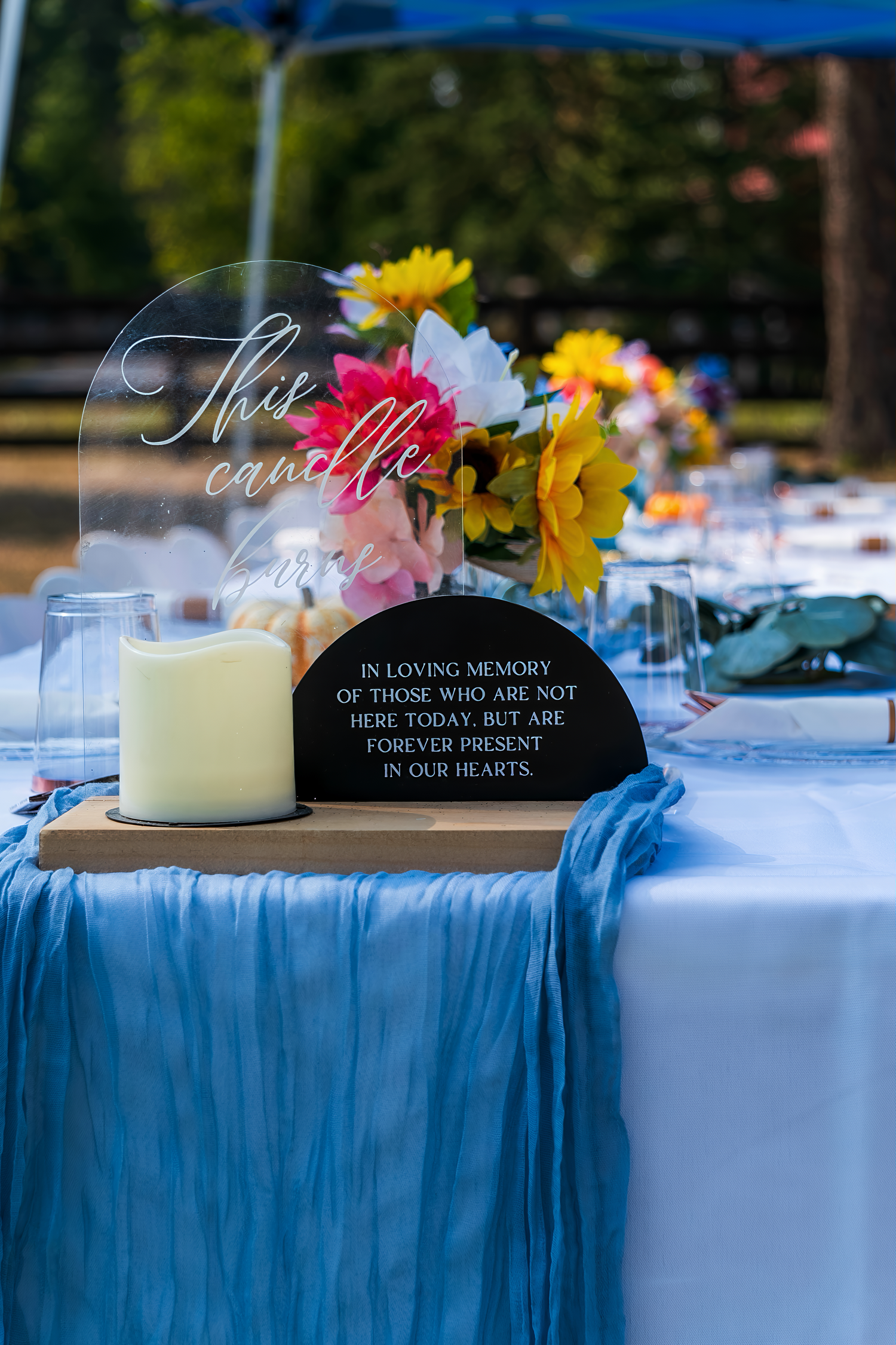 Wedding reception table with blue linens and memorial candle display.