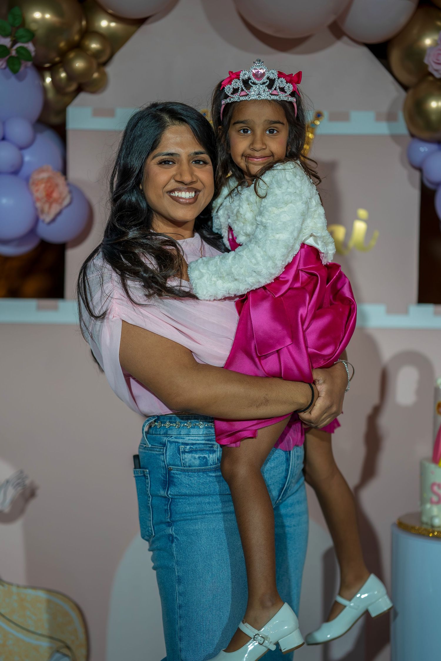 A joyful birthday celebration moment captured against a backdrop with balloons and party decorations.