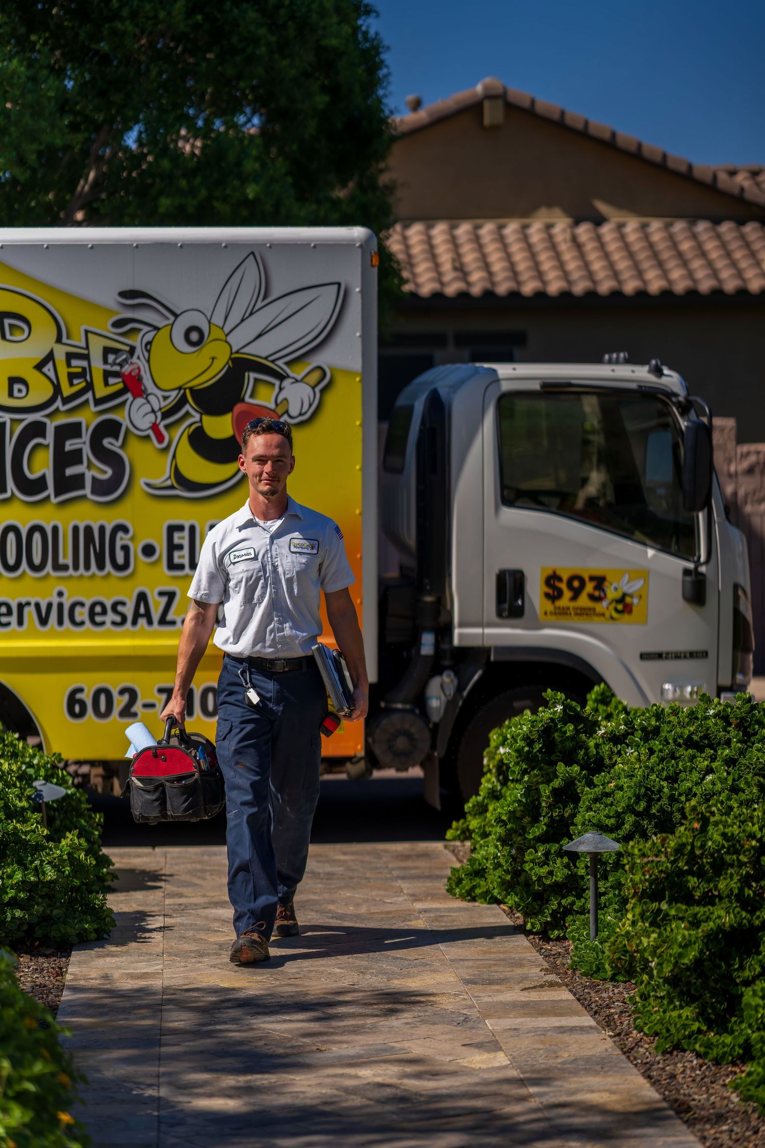 Service technician walking on paved pathway with company van in background.