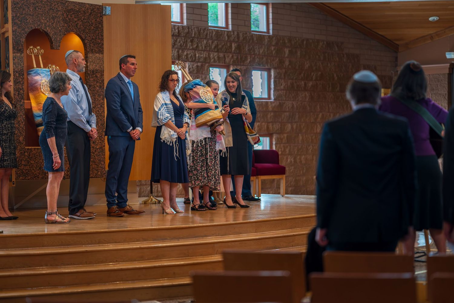 Group of people standing together during a church ceremony inside a modern wooden chapel.
