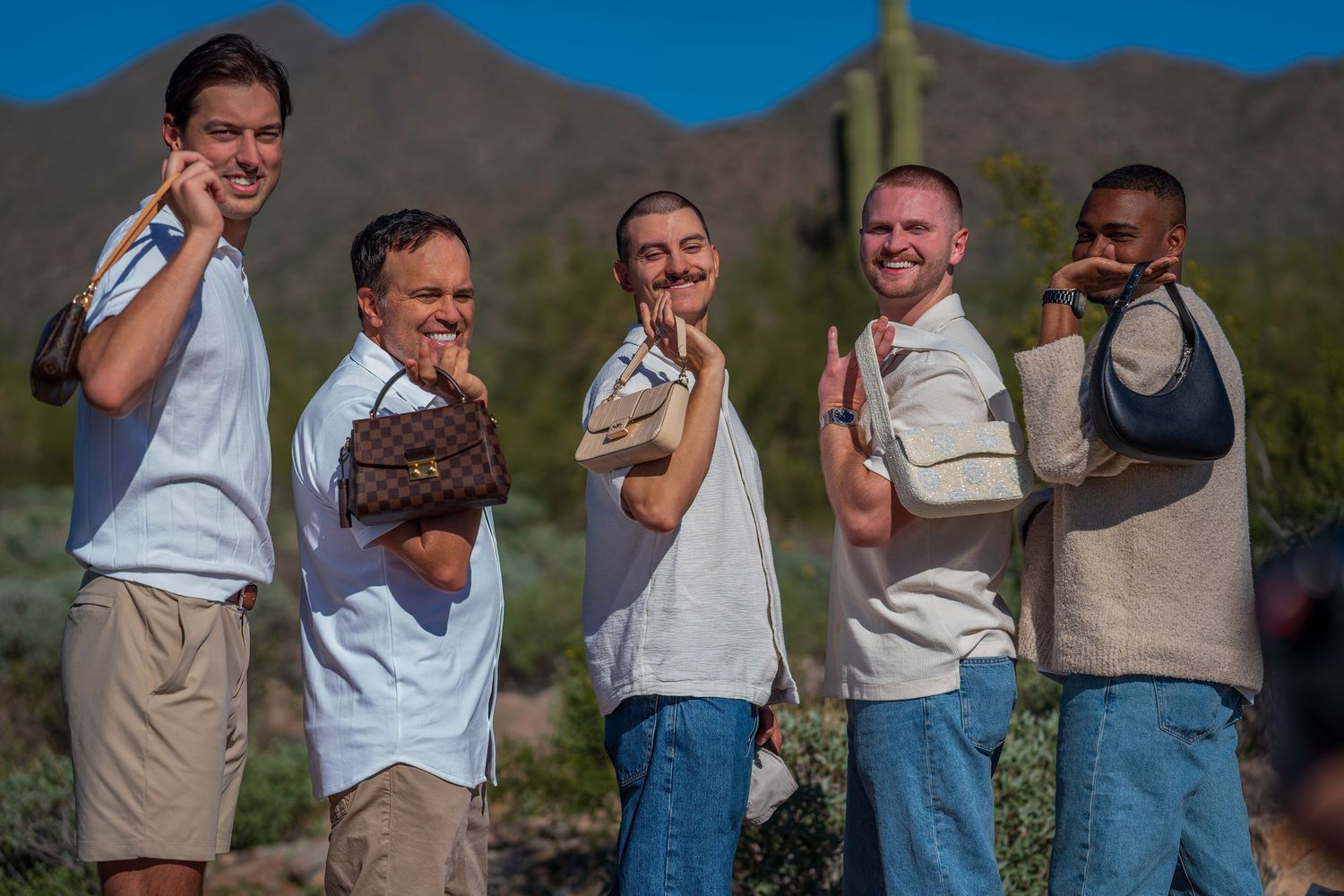 A playful group poses in a line against mountain scenery with saguaro cactus in the background.