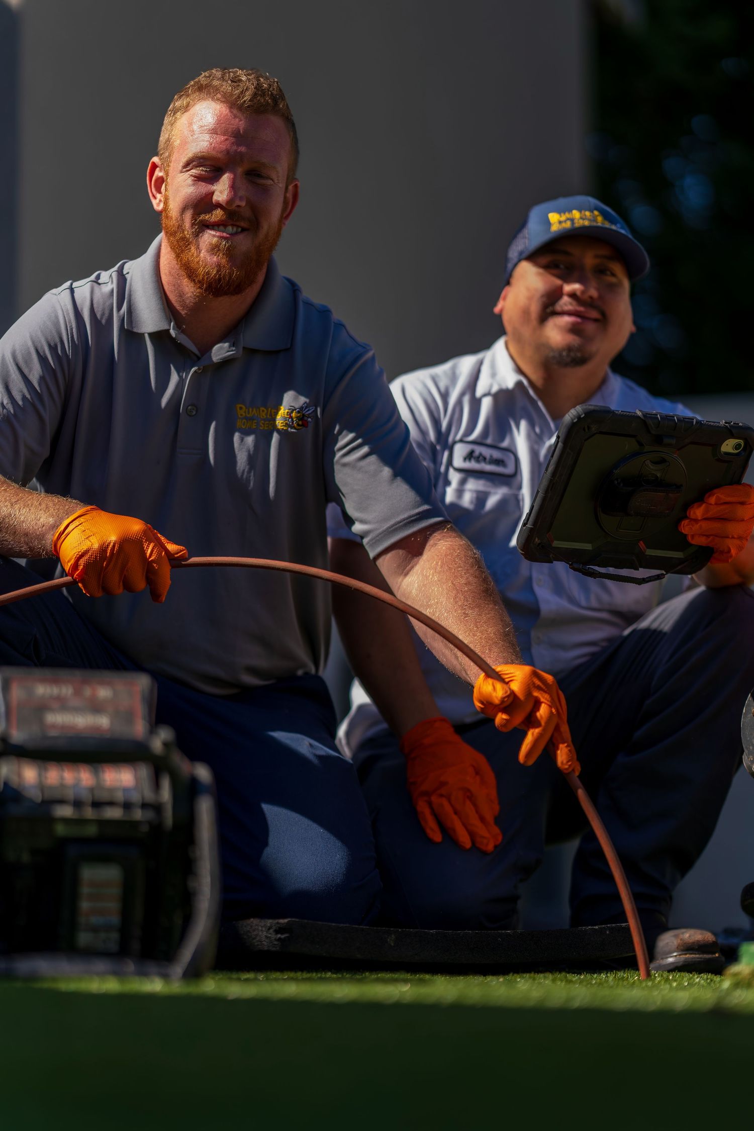 Plumbing technician in work uniform holding orange equipment during service call.