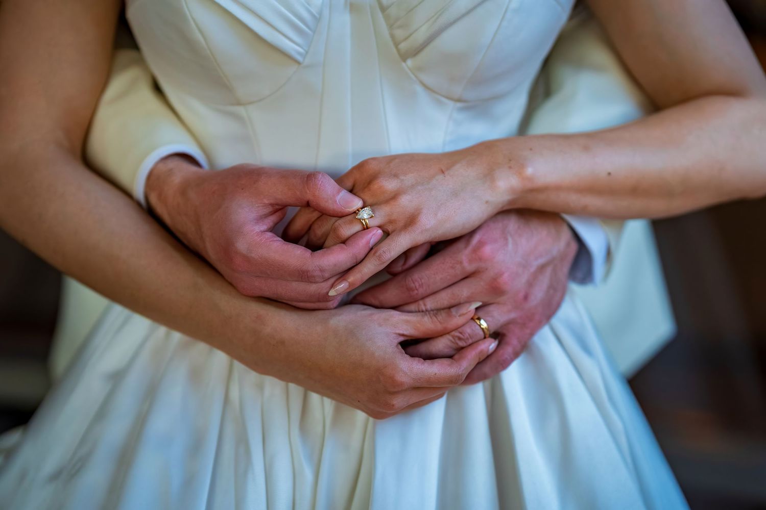 Close-up of hands and wedding rings in romantic moment.