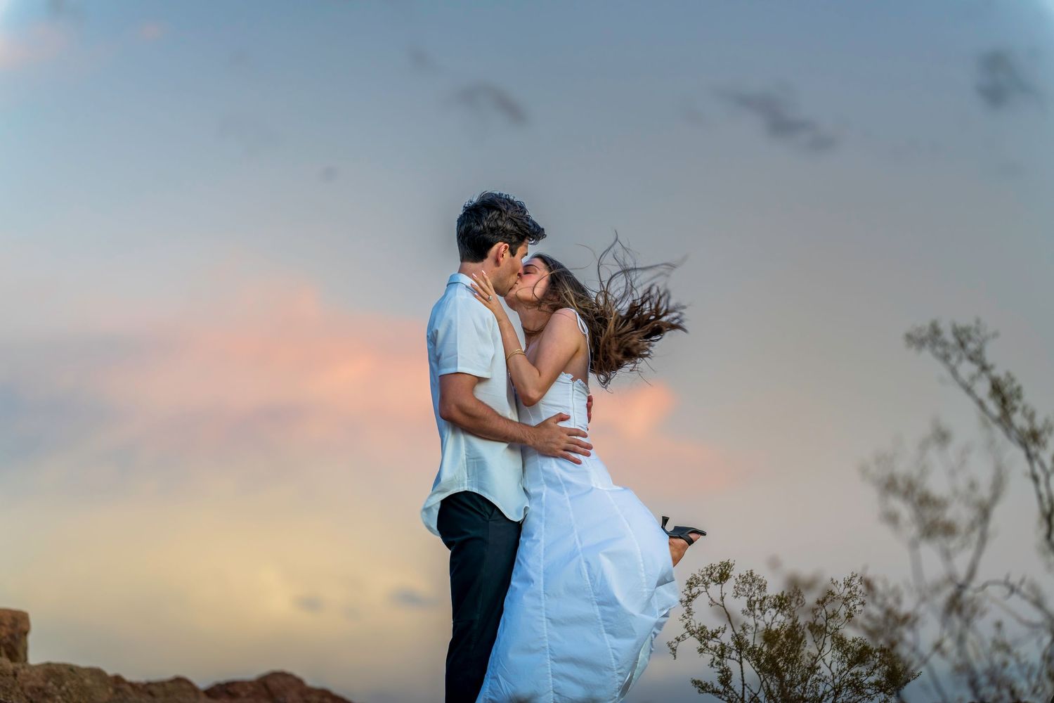 Two people share a playful dance move against the setting sun.
