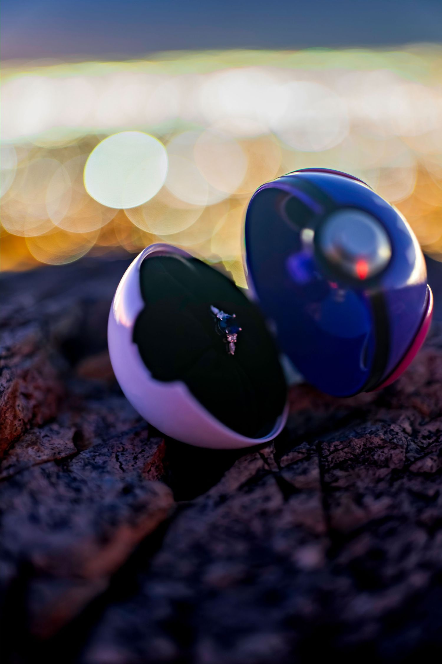 Open Pokemon Master Ball resting on a rock with a tiny Pokemon inside and bokeh city lights at night.