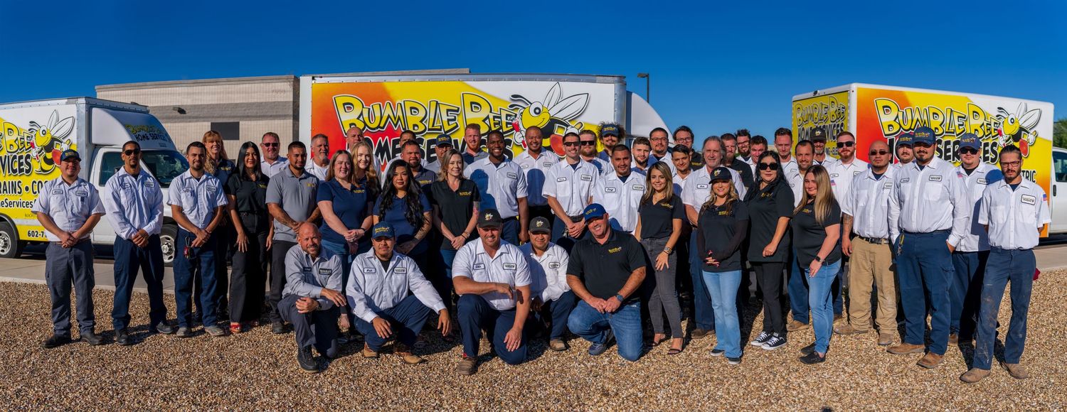 Panoramic view of plumbing company staff and vehicle fleet against blue sky.