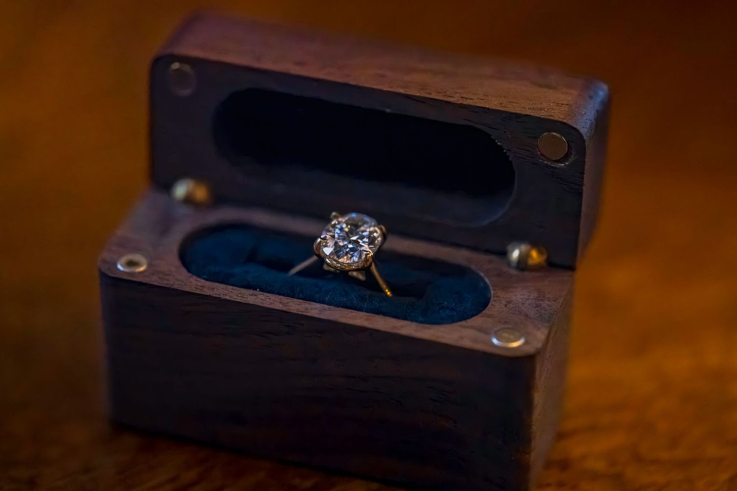 A sparkling diamond engagement ring displayed in an elegant wooden box.