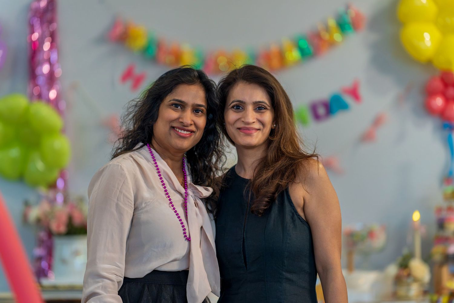 Friends celebrating at a party with bright decorations and balloons.
