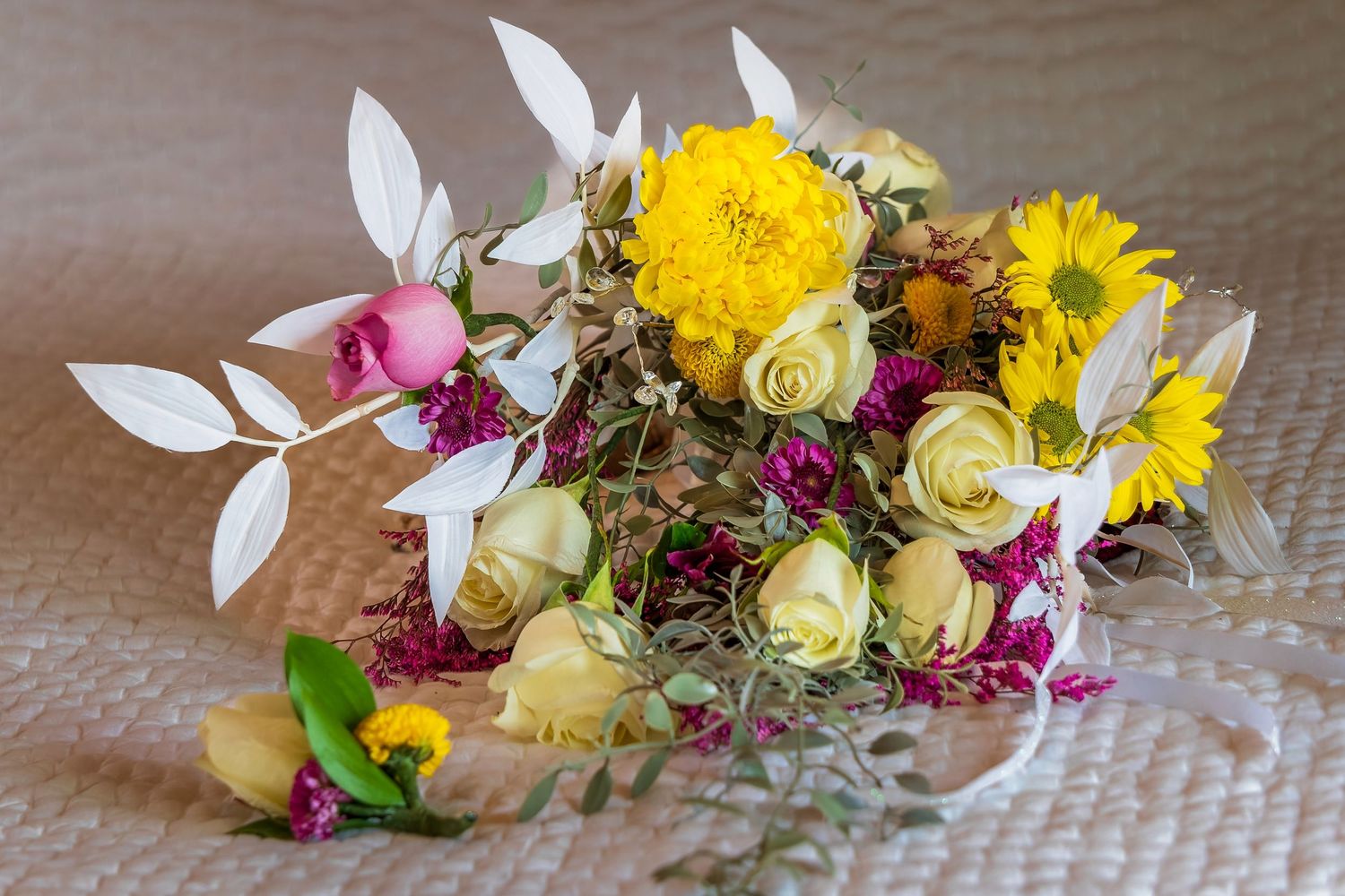 Colorful wedding flower arrangements featuring yellow sunflowers and pink roses on a table.