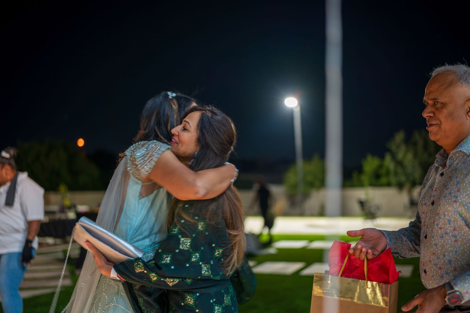 A nighttime embrace between guests at an outdoor celebration.