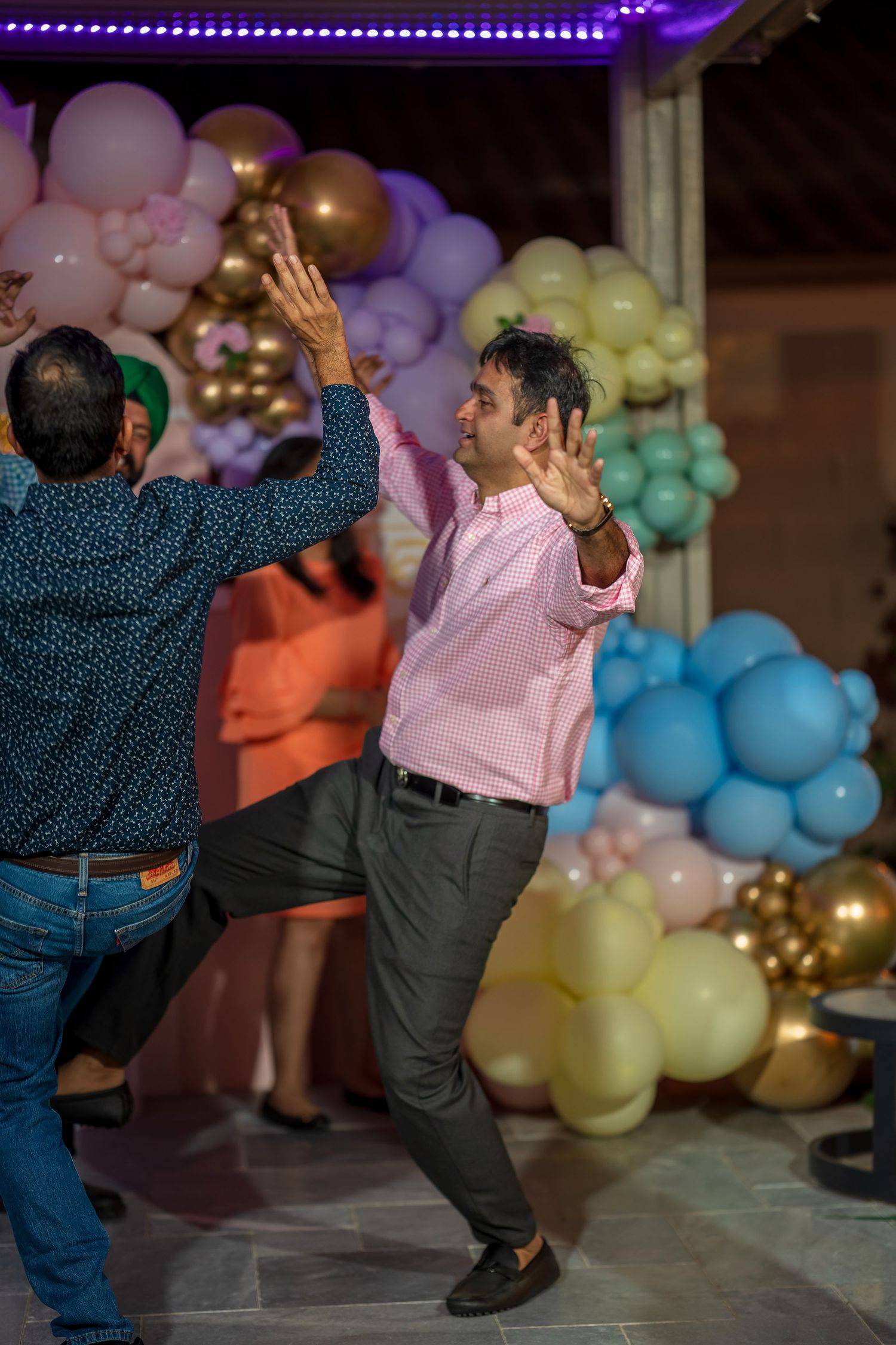 Energetic dance moves captured at a party with balloon decorations.