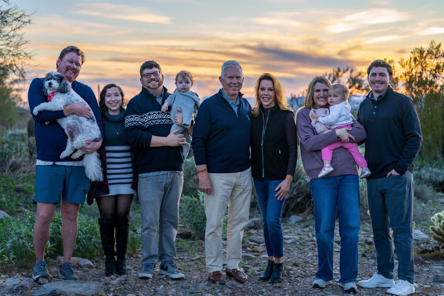 A group poses together outdoors at sunset with mountains in the background.