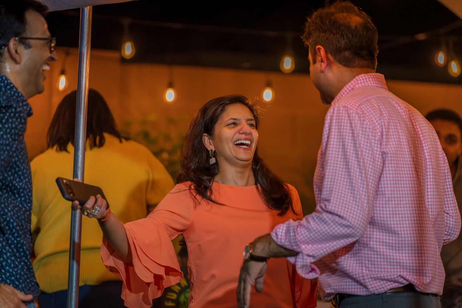 People enjoying a lively party celebration with colorful lights and decor in the background.