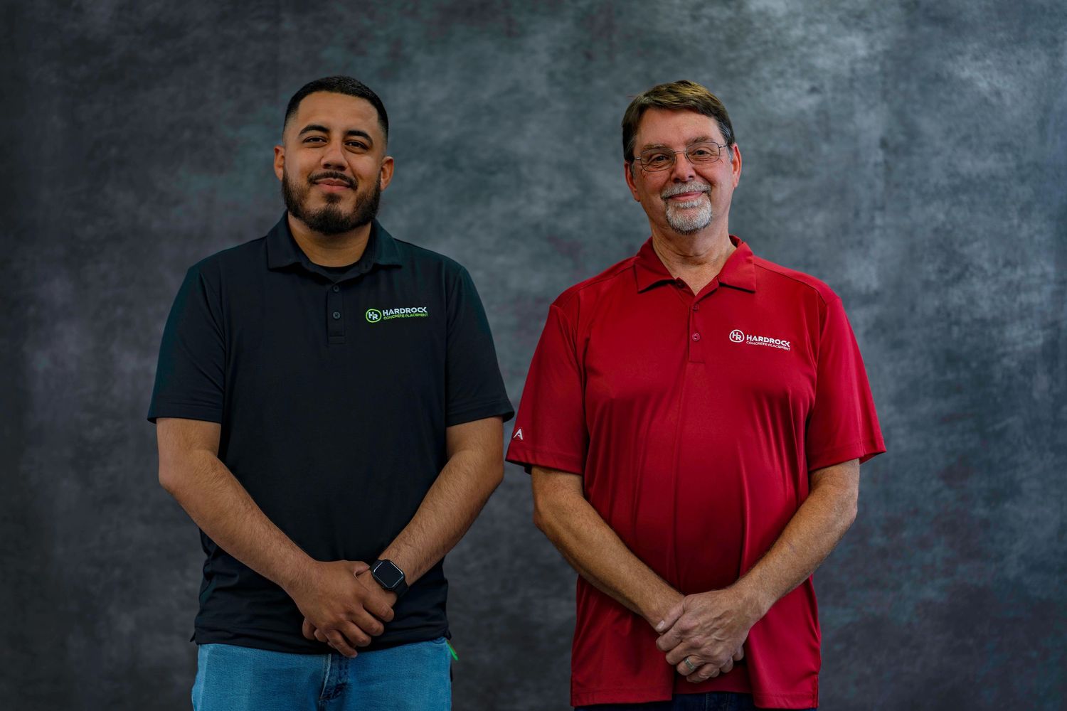 Colleagues in casual business attire pose together against textured gray background.