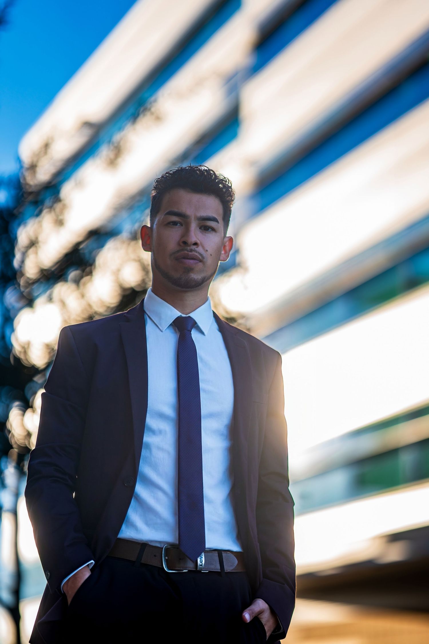 Stylish business portrait with modern architecture and sunlight creating dramatic backdrop.