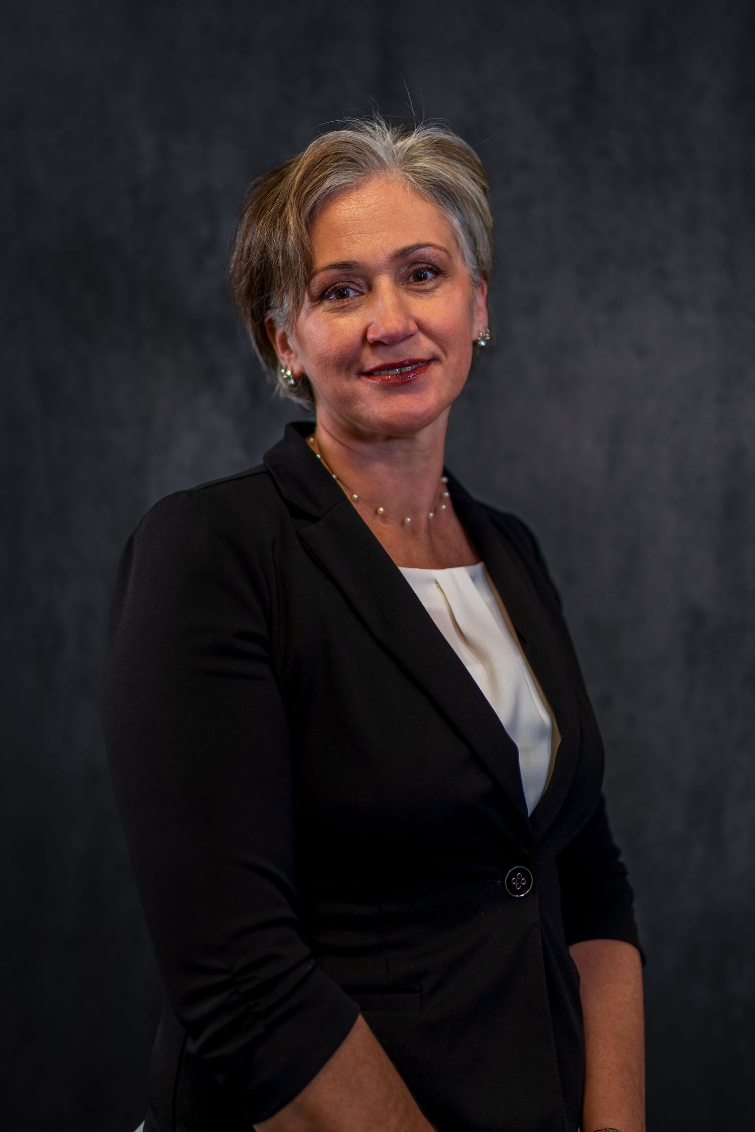 Professional studio portrait against dark background featuring business attire.