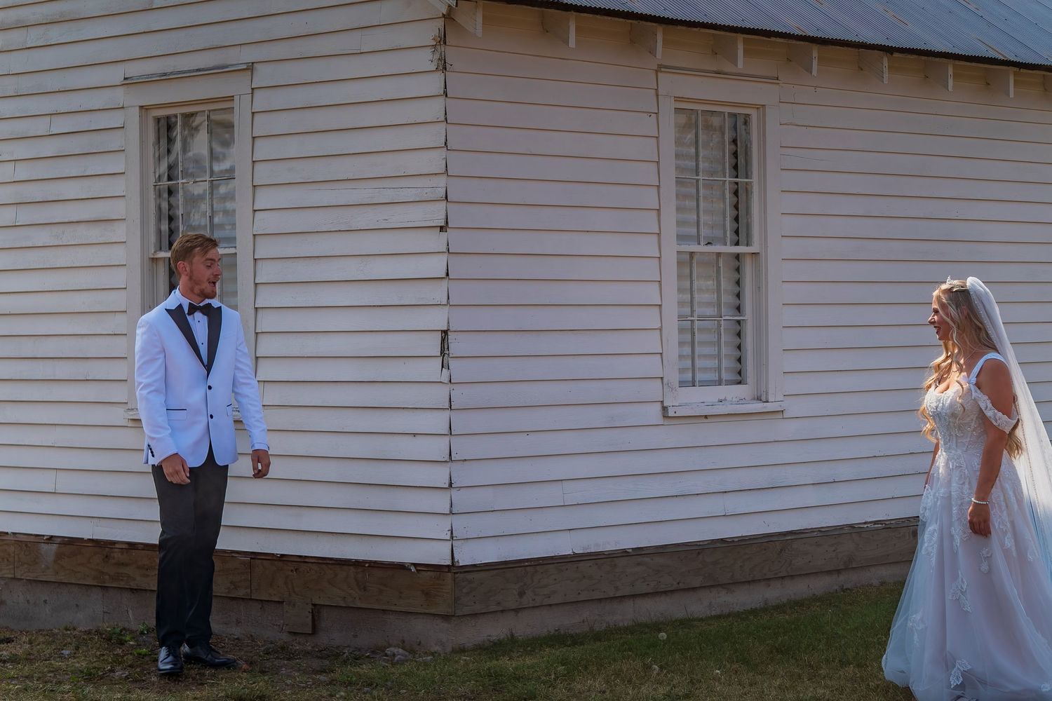 White clapboard church or chapel exterior with wedding couple in the distance.
