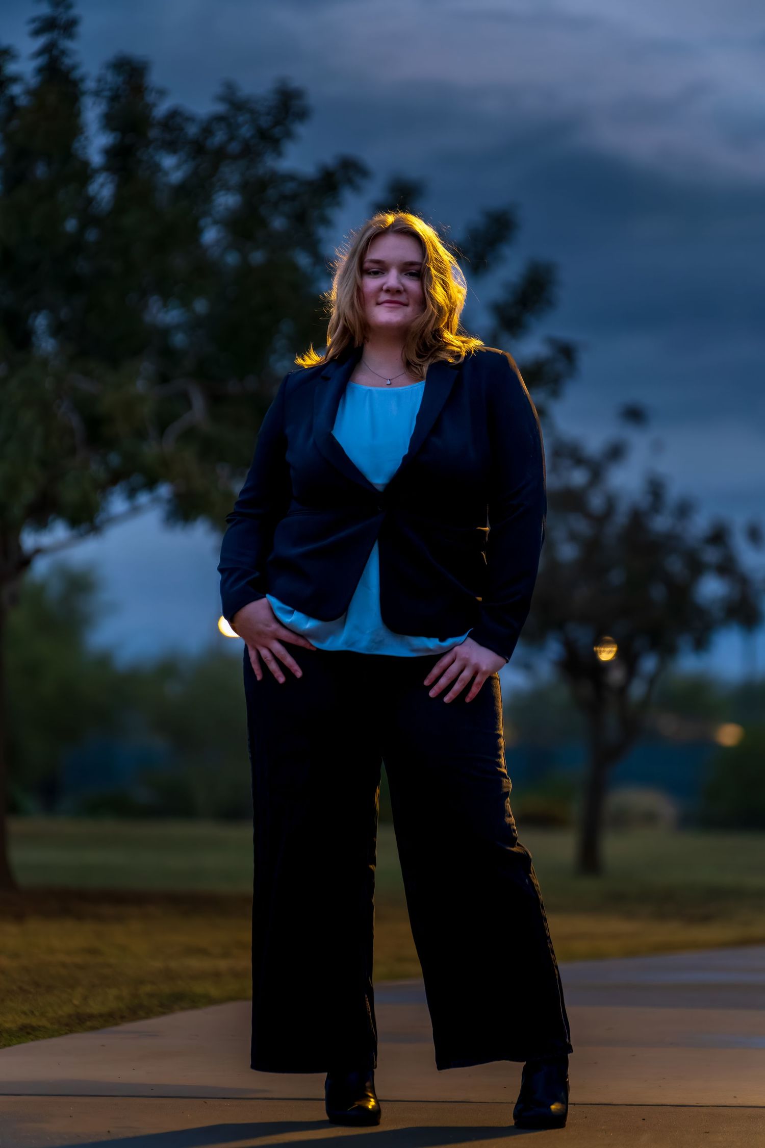 Casual outdoor portrait session on concrete path with natural sunset backdrop.