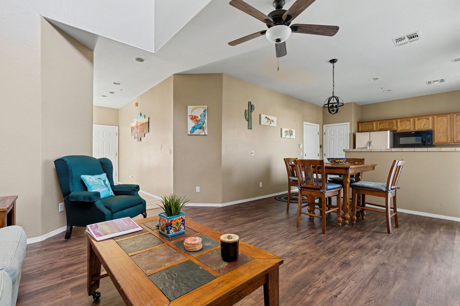 Open-concept living and dining area with hardwood floors, ceiling fan, and modern furnishings in a bright home.