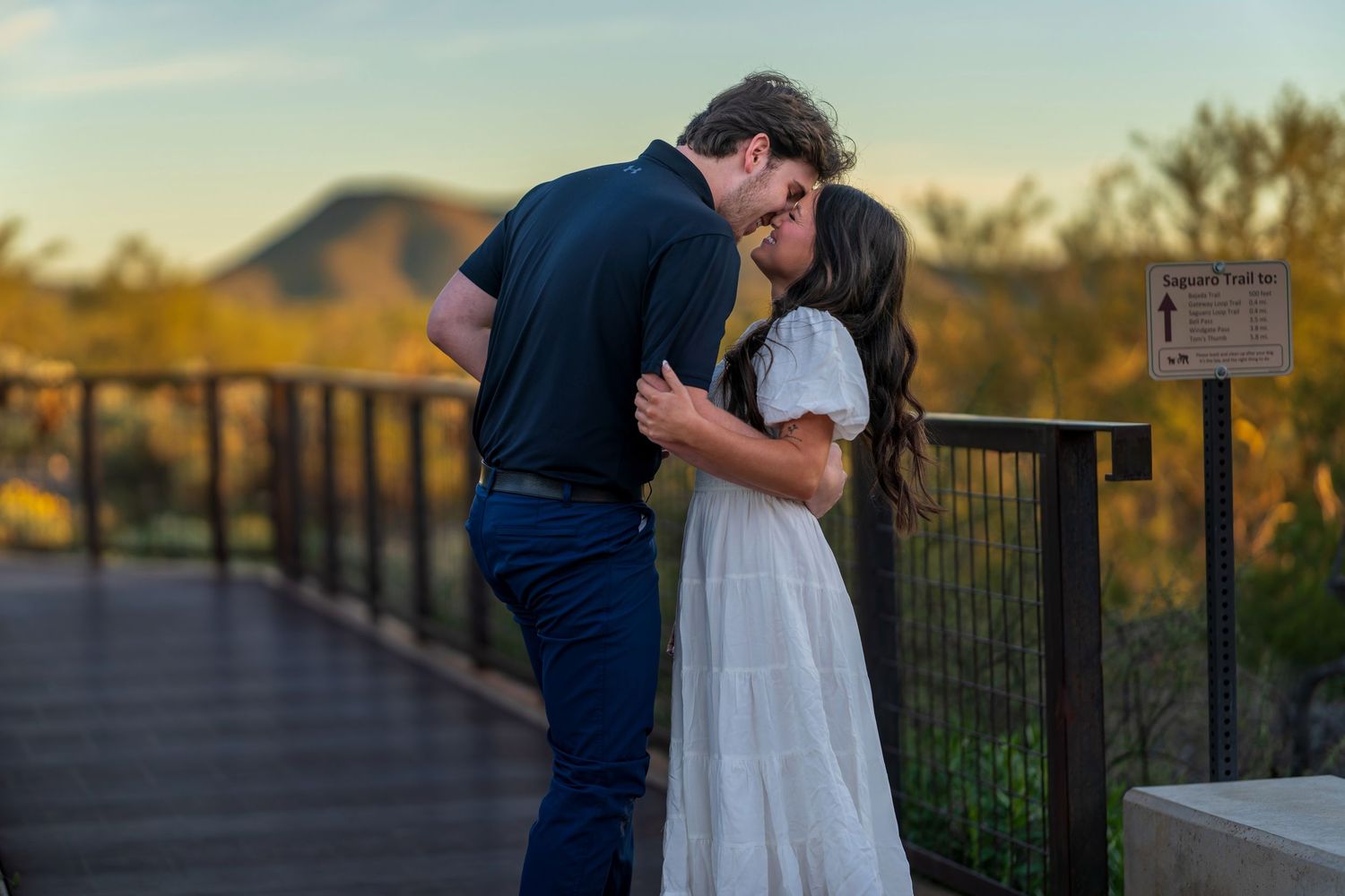 A romantic proposal scene unfolds on a desert observation deck with mountains visible in the distance.
