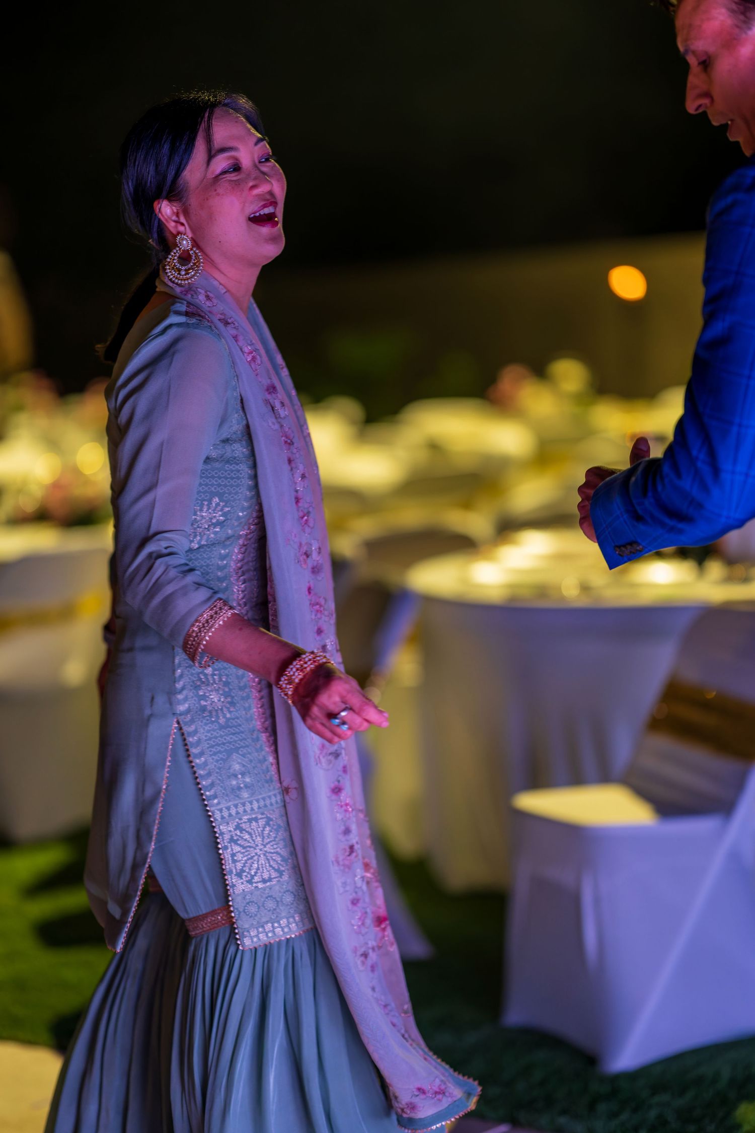 Guests dancing and celebrating at an evening party with colorful lighting and traditional attire.