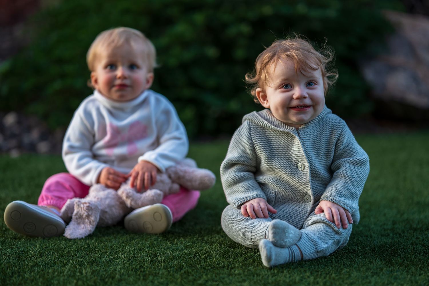 Baby wearing light blue clothing sitting on grass outdoors.