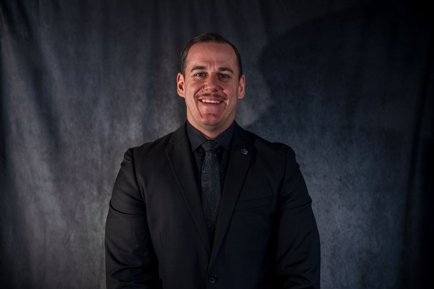 Studio headshot with moody lighting against dark backdrop.