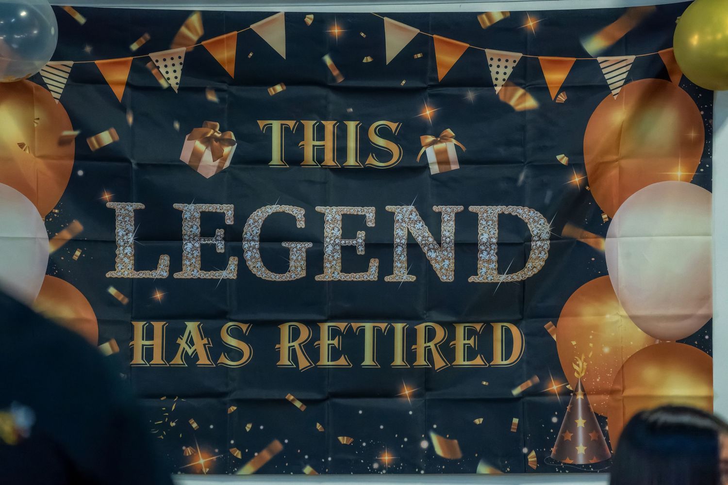 Decorative retirement party banner with gold balloons and bunting.