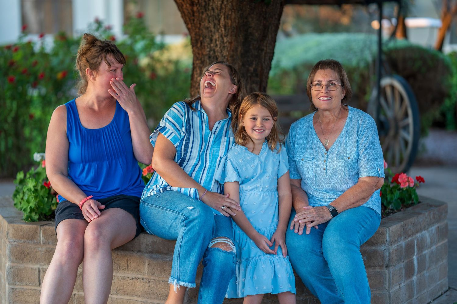 Family members gather under a tree for casual outdoor portraits in coordinated blue clothing.
