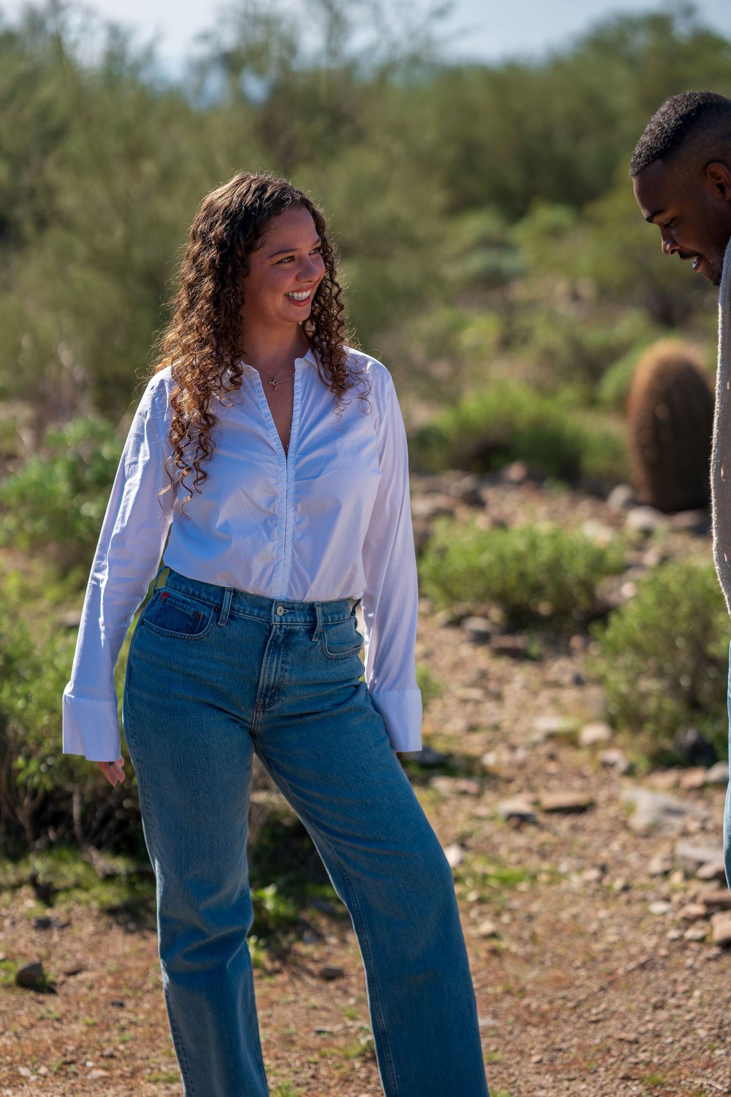 A casual outdoor portrait in the desert with cacti and mountains visible.