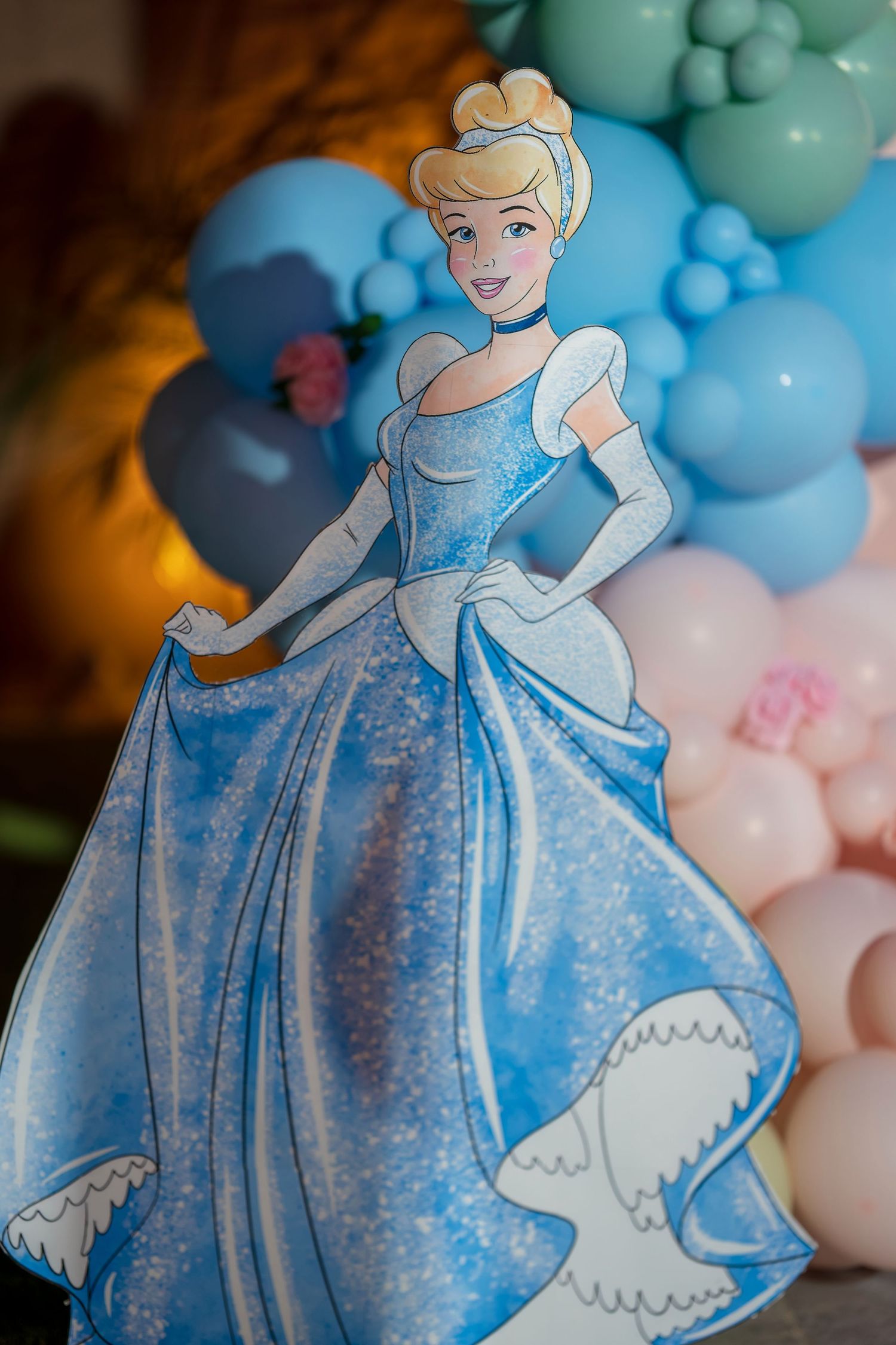 Disney princess cutout in a sparkling blue ballgown against pastel balloon decorations.