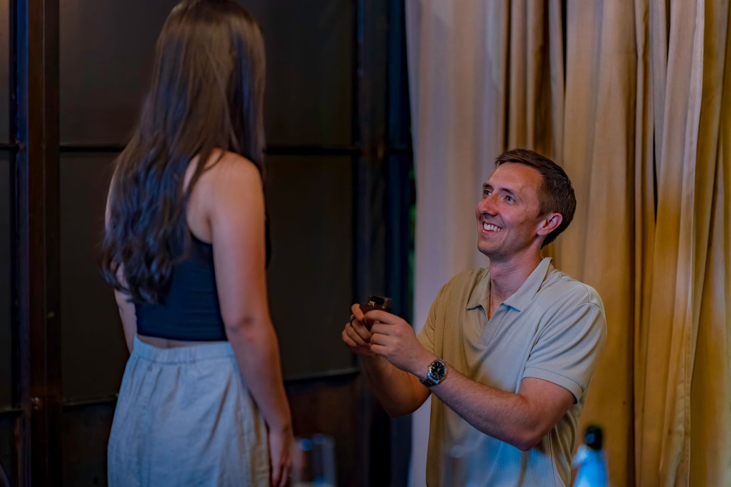 Candid moment captured during a romantic restaurant proposal.