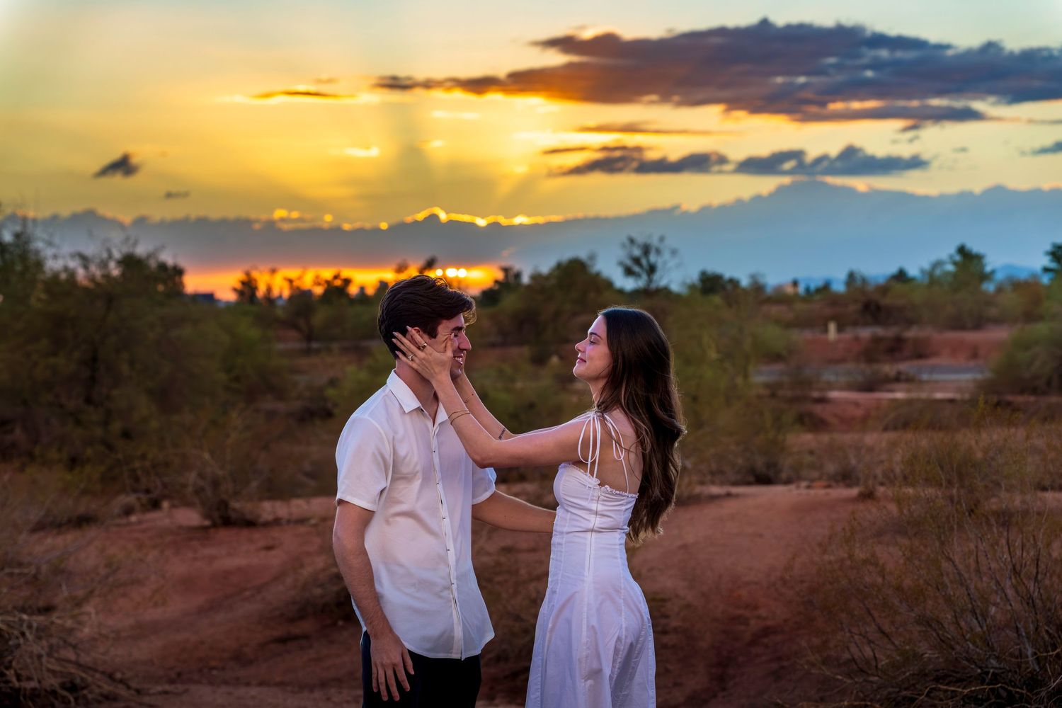 Romantic desert engagement photos with dramatic orange and purple sunset sky.