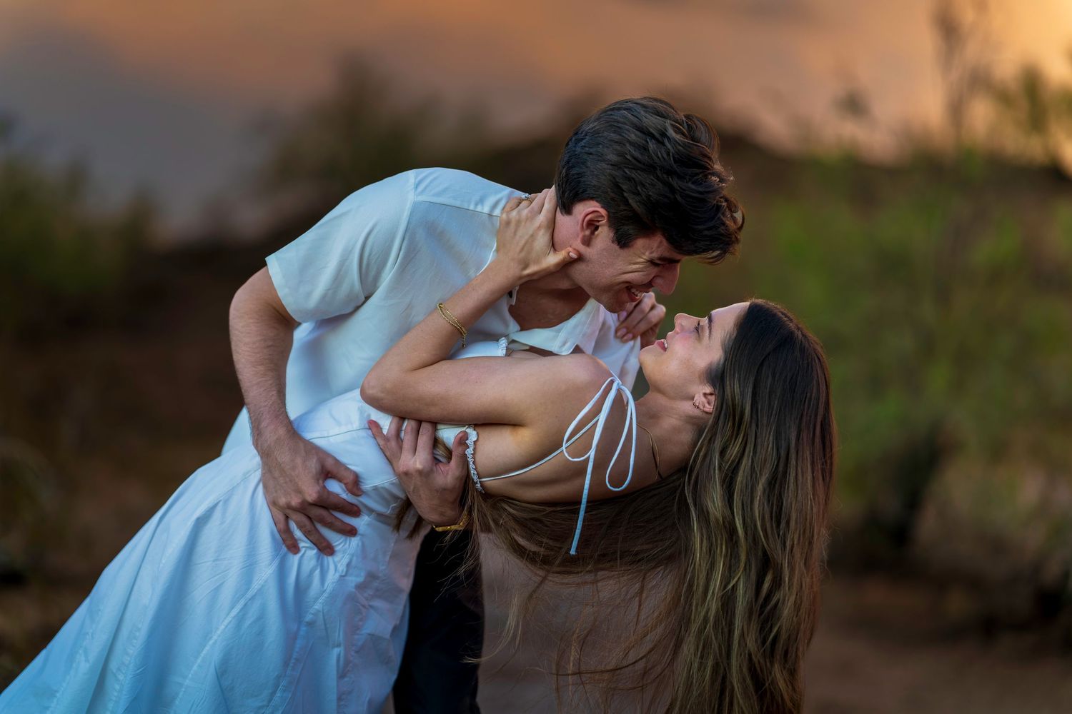 A romantic dip pose between a couple during golden hour in a natural outdoor setting.