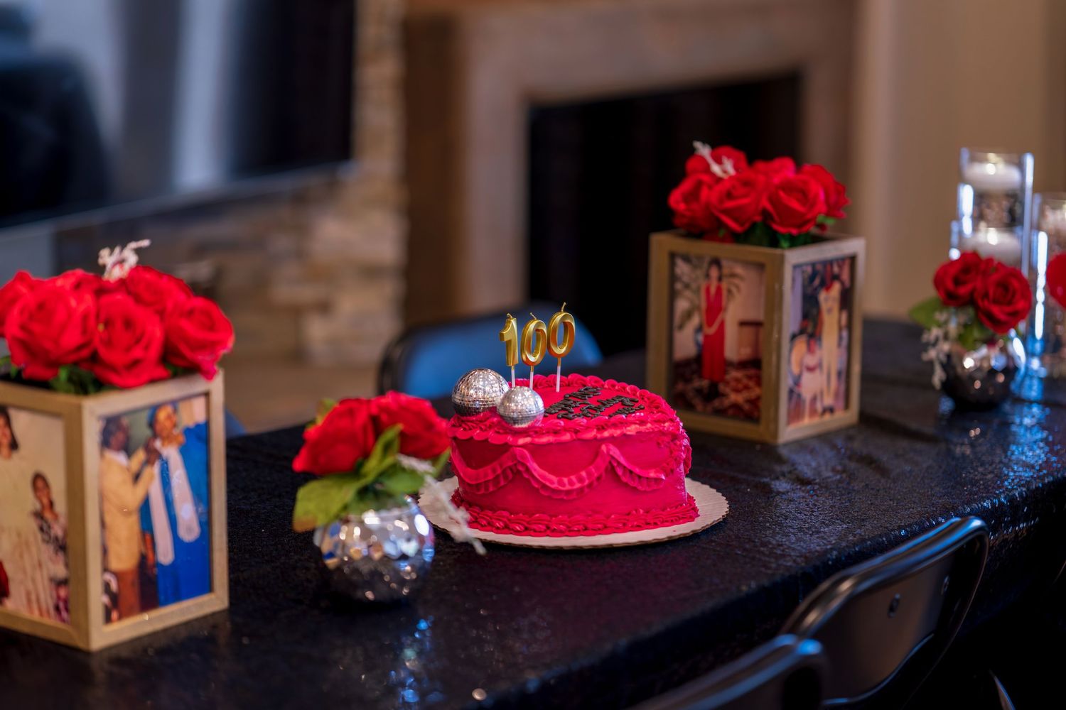A red birthday cake with decorative lanterns and roses on a dark table.