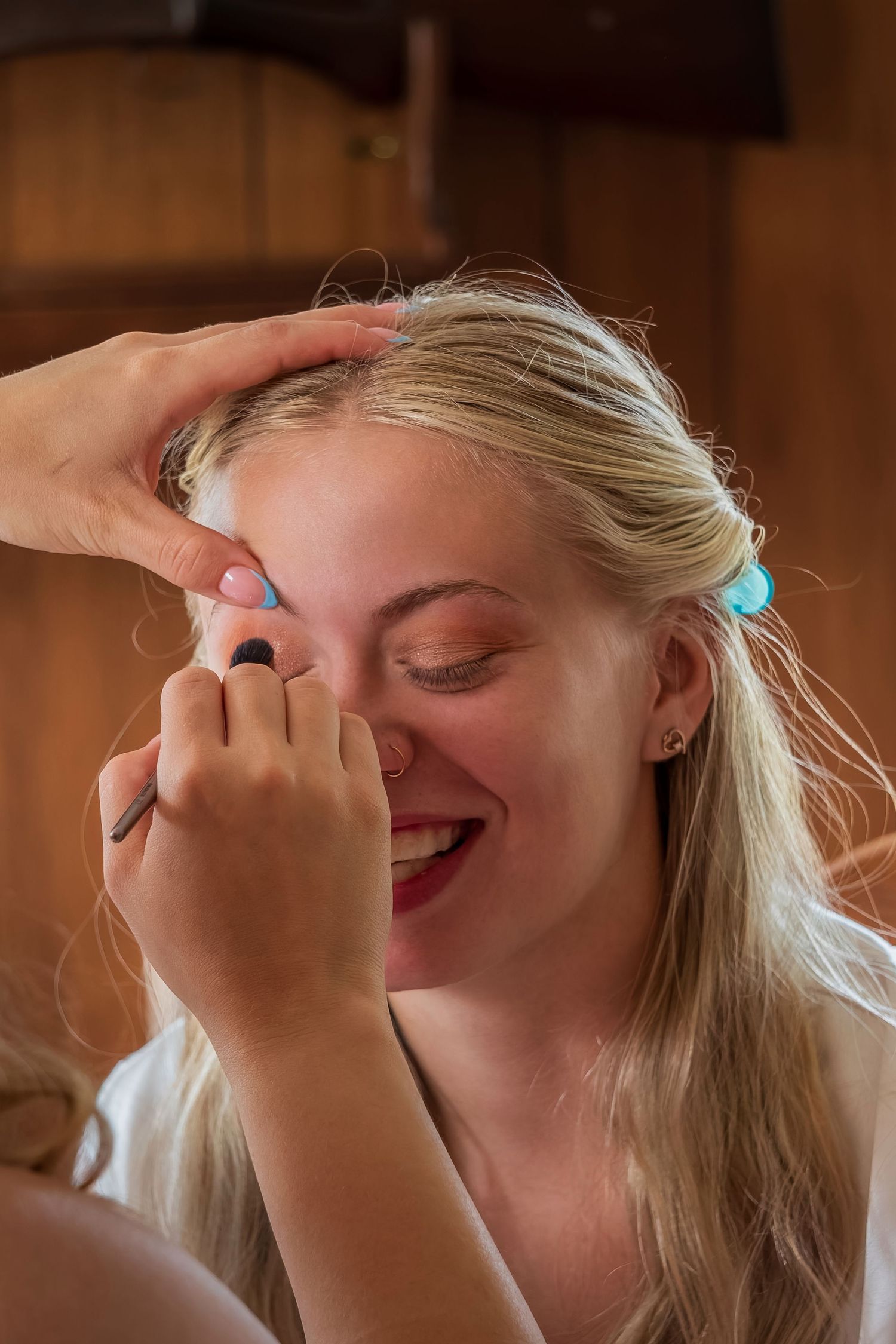 Makeup application in progress in rustic wooden setting.