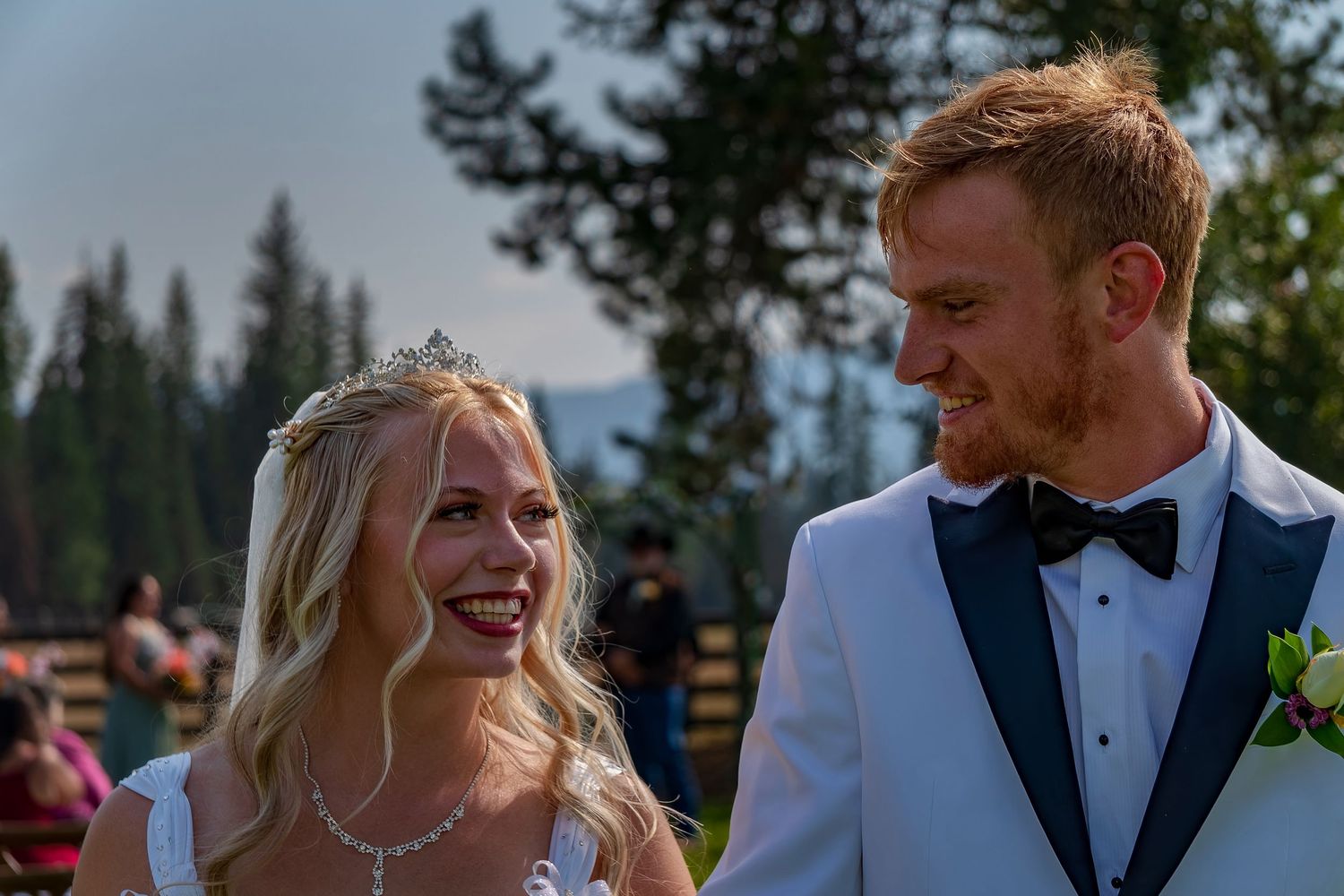 A happy couple shares genuine laughter during their outdoor forest wedding.