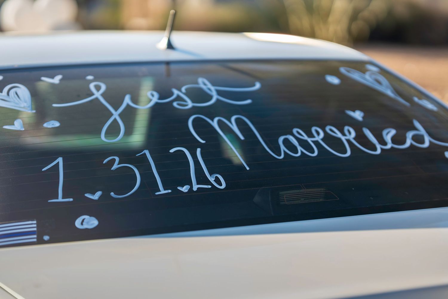 Car rear window decorated with Just Married and wedding date 1.31.26 in white lettering.