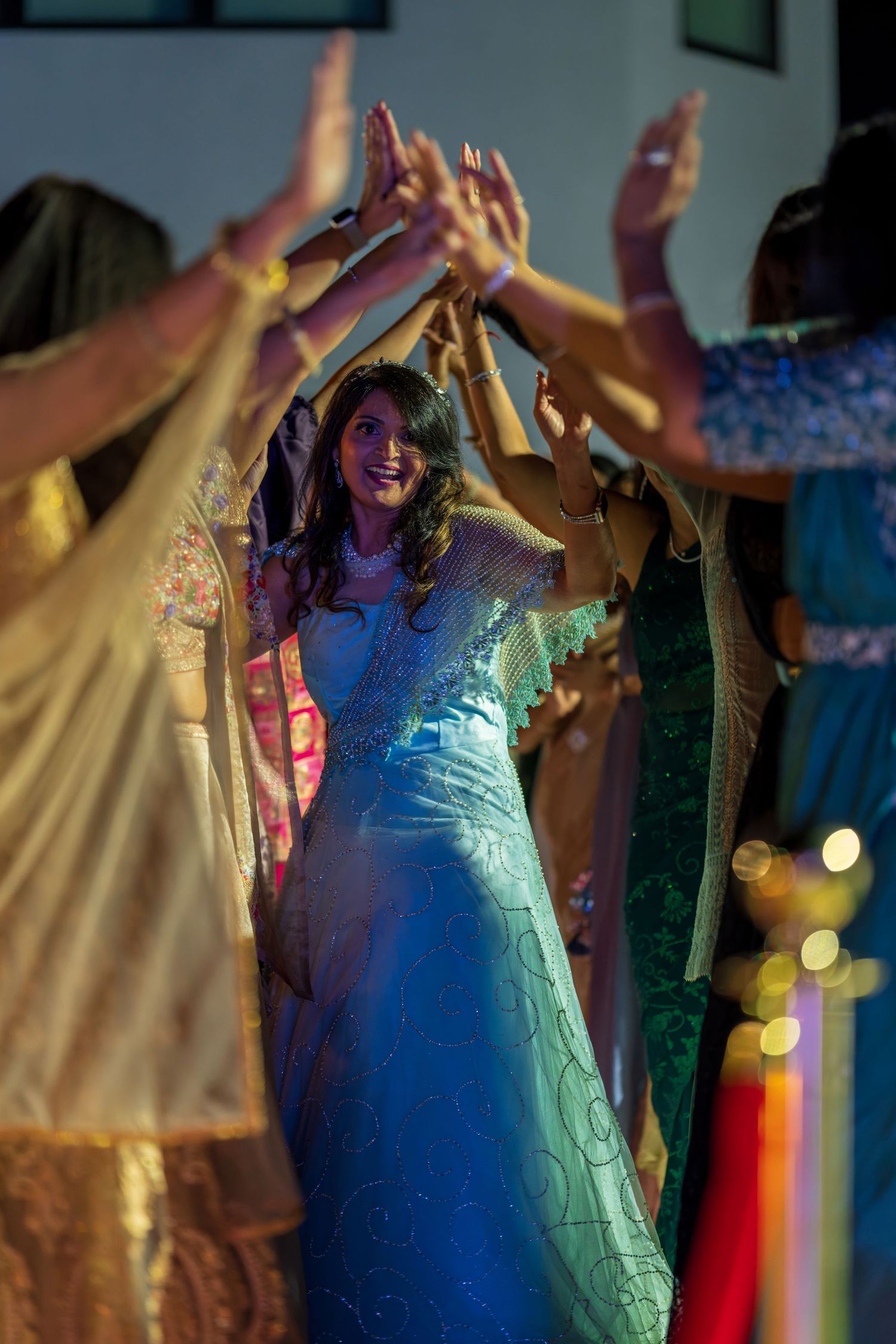 Dancers in formal wear express joy with raised arms under blue and yellow stage lighting.